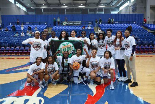 Women holding a banner and trophy posing for a team photo