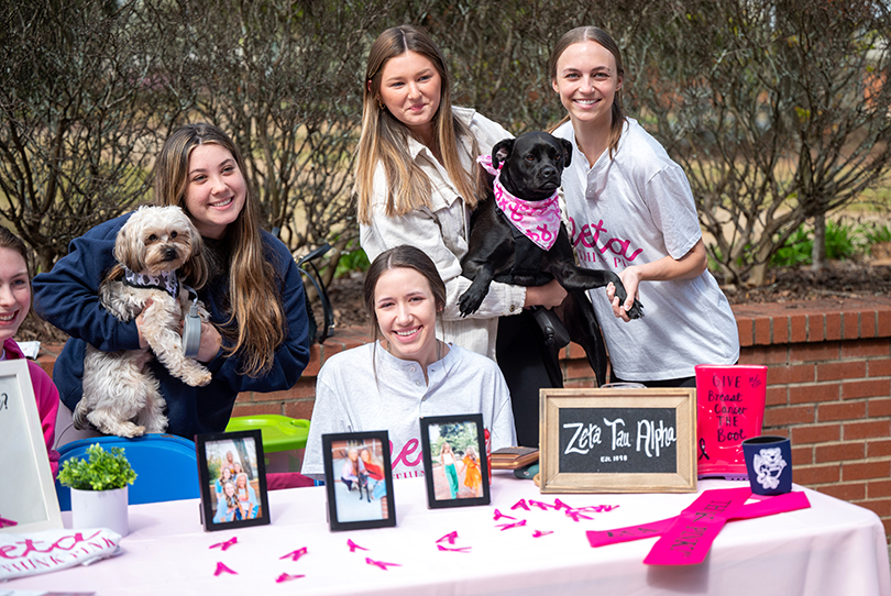 Students with small dogs sitting at a table outside