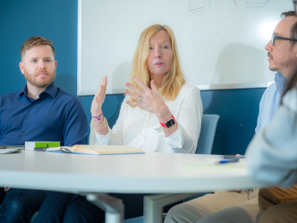 A team of four scientists, two women and two men, sit around a table and talk.