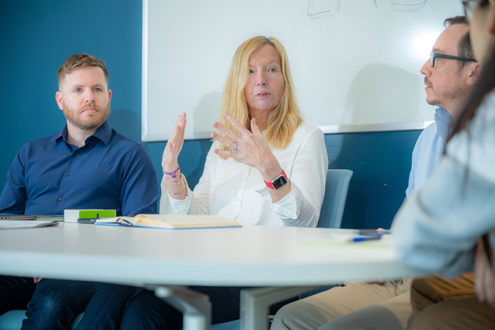 A team of four scientists, two women and two men, sit around a table and talk.