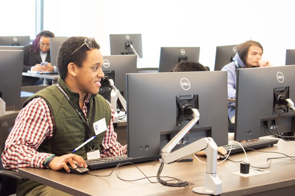 Student smiling while doing work on computer.