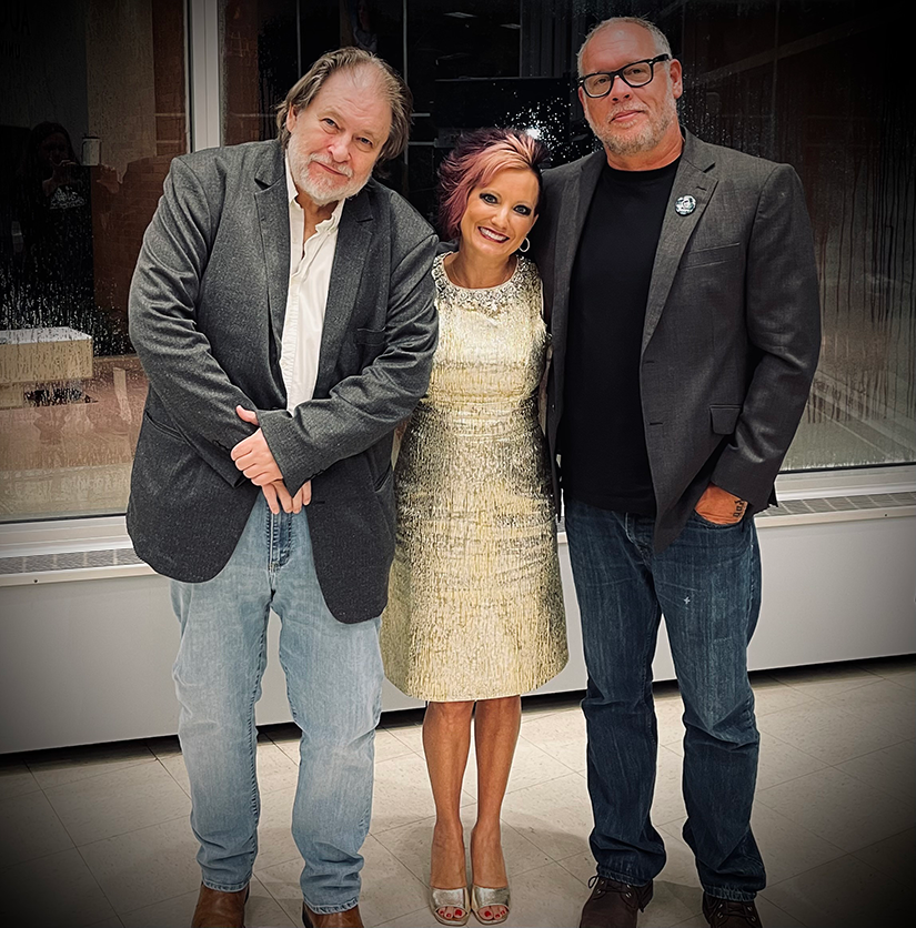 Two men and a man smile and pose for a photo.