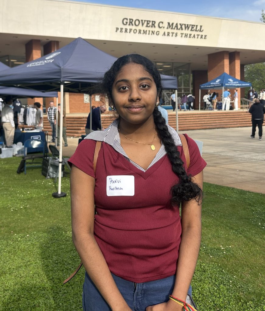 A woman smiles for a photo while standing in front of a theatre hosting a tabling event.