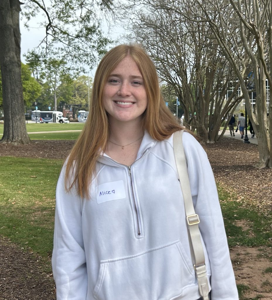 A woman smiles for a photo while standing outdoors.