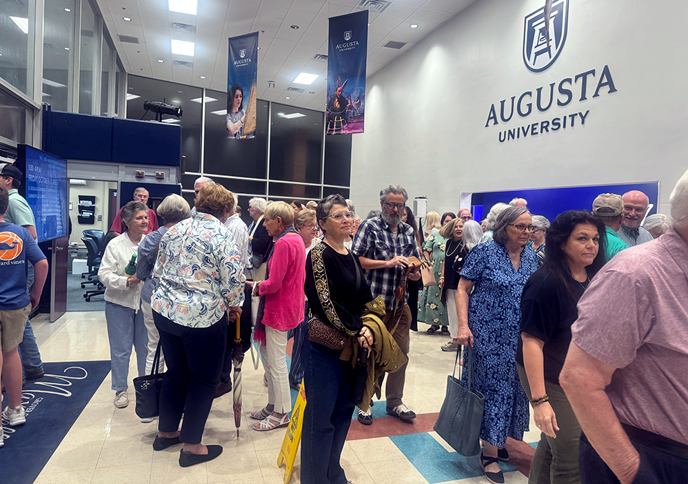 A crowd of people gathered in the lobby of a university theatre.