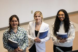 3 women standing smiling holding books