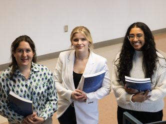 3 women standing smiling holding books