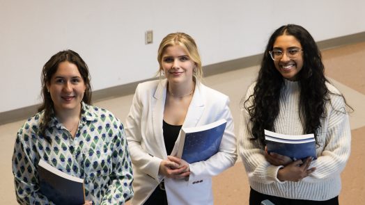 3 women standing smiling holding books