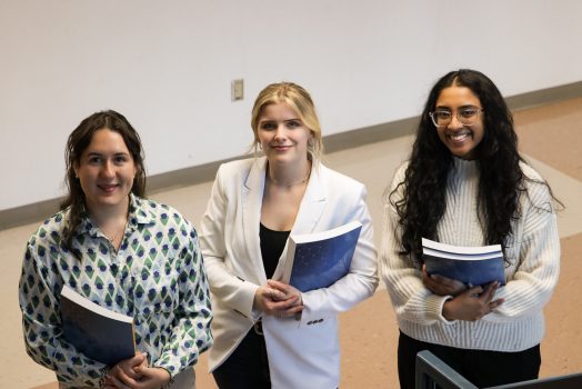 3 women standing smiling holding books