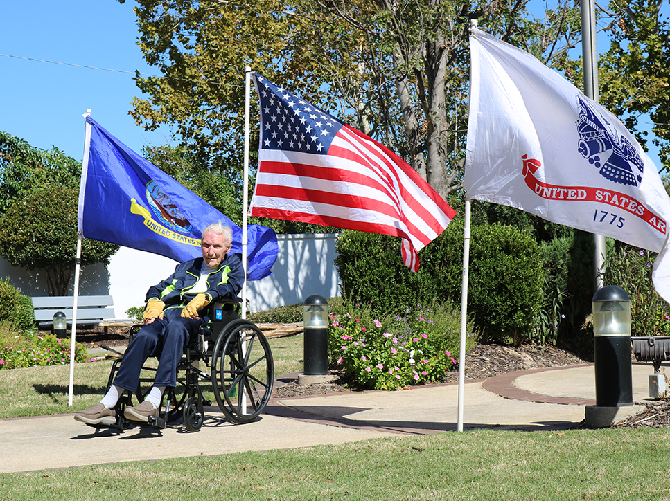 Man sitting in a wheelchair in front of flags