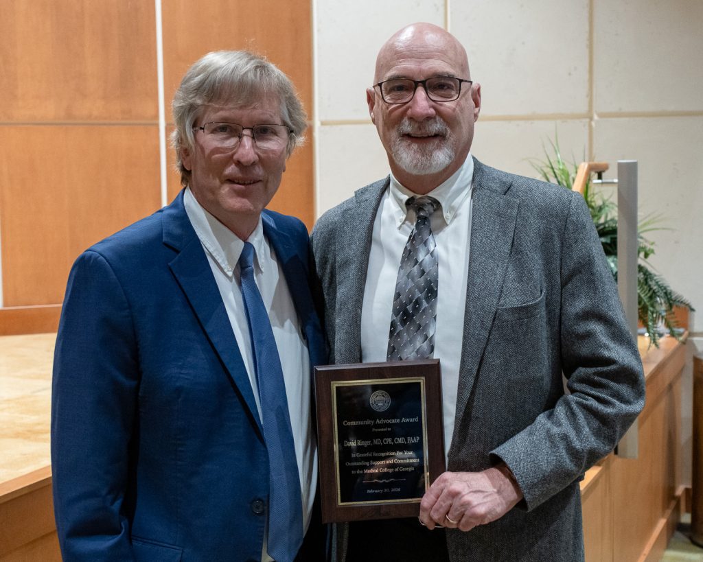 Two men standing with one of them holding a plaque