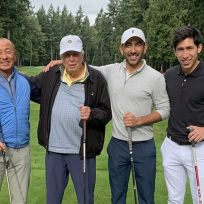 four men stand with golf clubs
