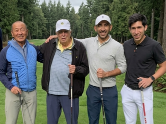 four men stand with golf clubs