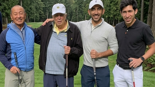four men stand with golf clubs