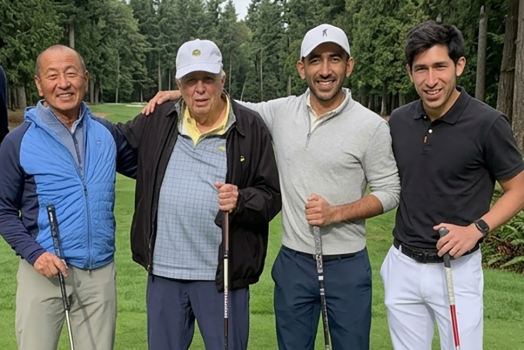 four men stand with golf clubs
