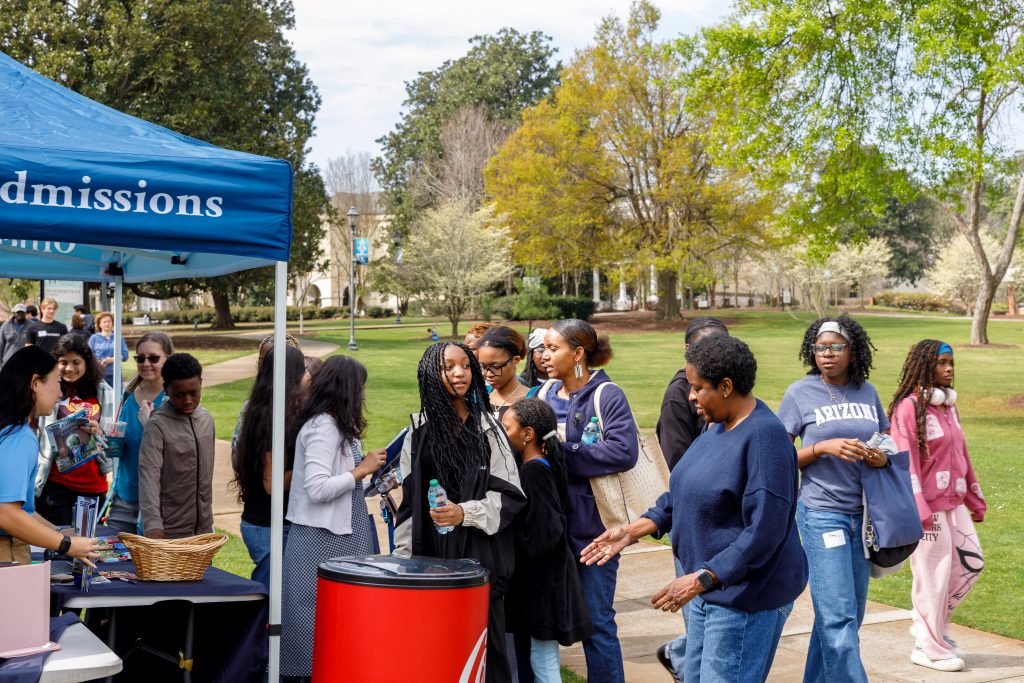A large group of women stand around an outdoor tabling tent.