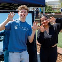 A man and woman hold up their hands to imitate a paw shape while smiling for a photo.