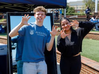 A man and woman hold up their hands to imitate a paw shape while smiling for a photo.