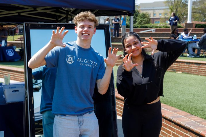 A man and woman hold up their hands to imitate a paw shape while smiling for a photo.