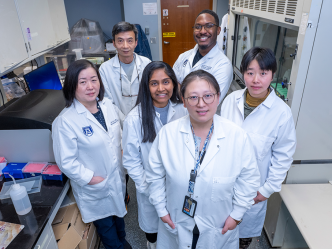 A group of scientists in lab coats pose for the camera.