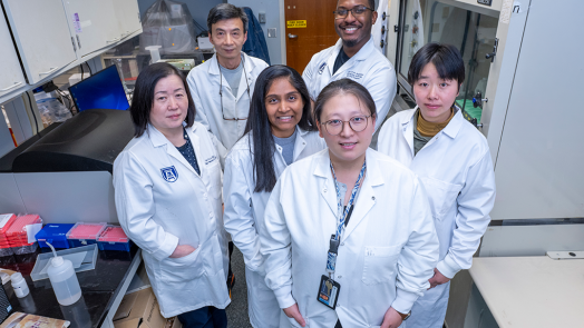 A group of scientists in lab coats pose for the camera.