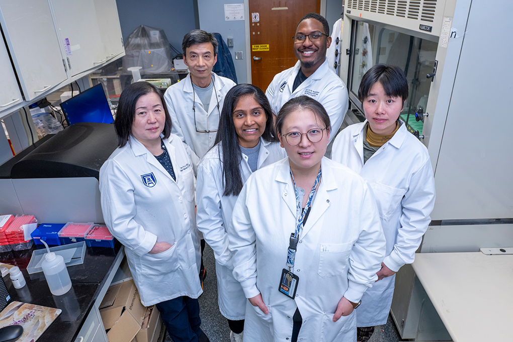 A group of scientists in lab coats pose for the camera.