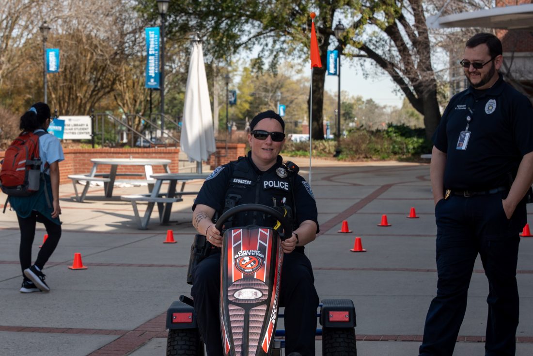 A police officer drives a pedal kart outdoors.
