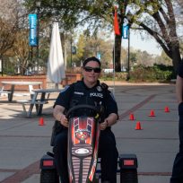 A police officer drives a pedal kart outdoors.