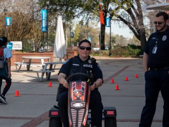 A police officer drives a pedal kart outdoors.