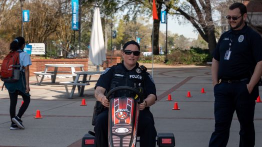 A police officer drives a pedal kart outdoors.