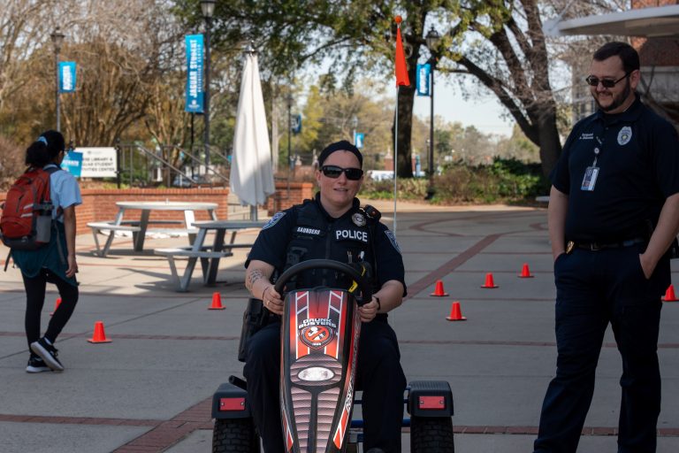 A police officer drives a pedal kart outdoors.