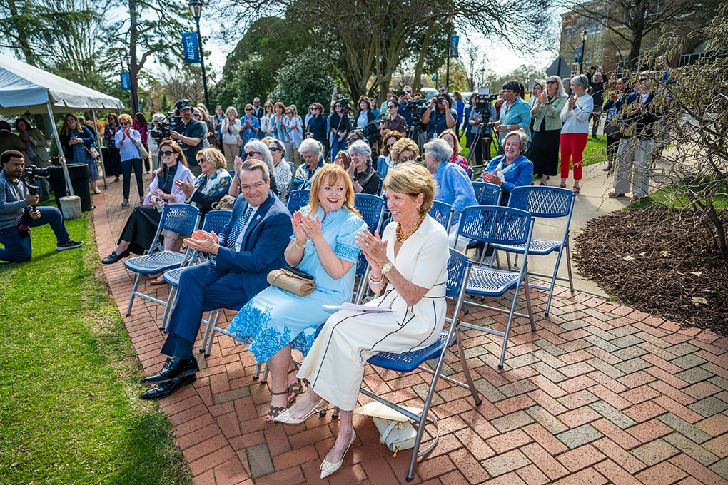 A crowd of people clapping, some sitting and some standing