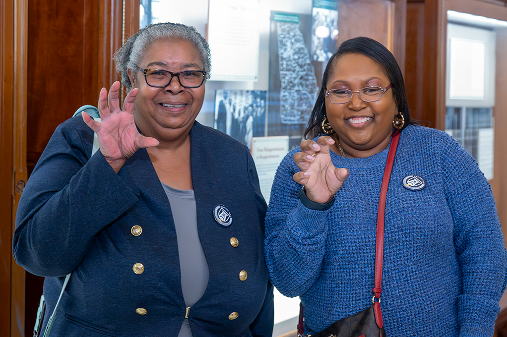 Two women smile holding up one hand like a claw.