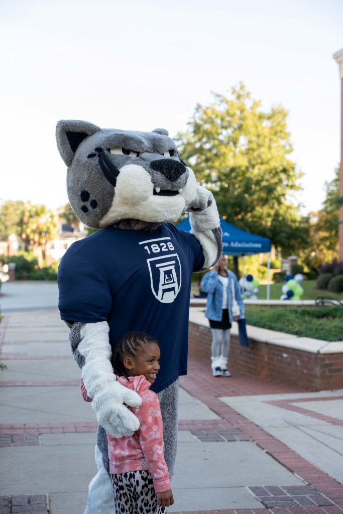 Augusta University mascot poses with for a photo with a young female child. 
