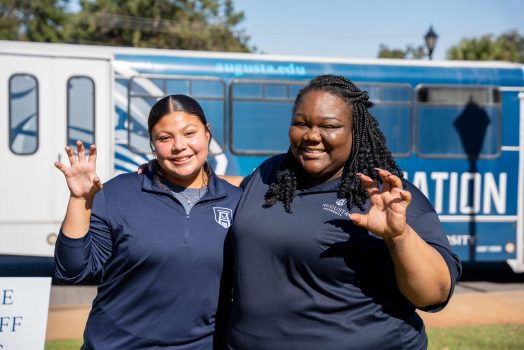 Two women smiling at the camera while holding up their hands in a paw pose.