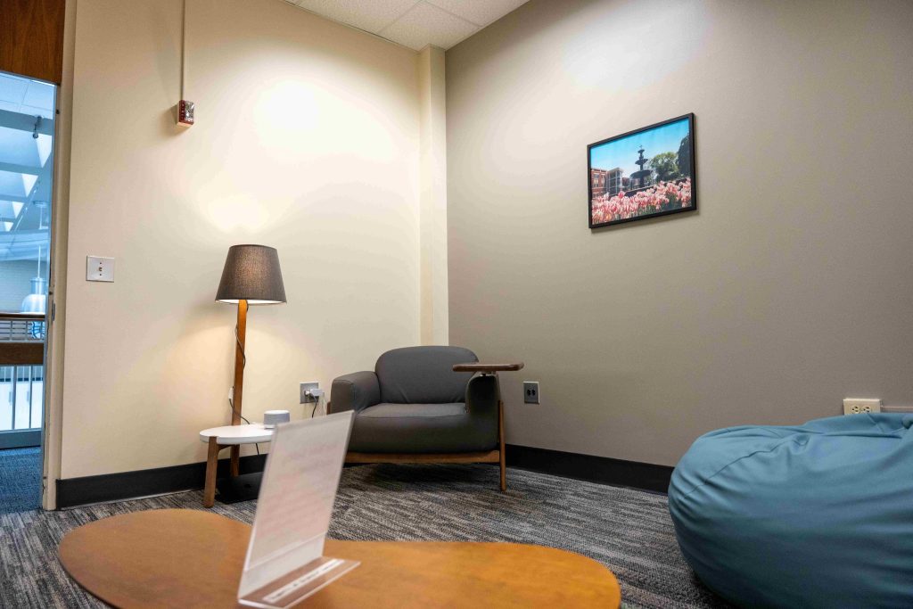 A room with low lighting, an upholstered chair and a beanbag.