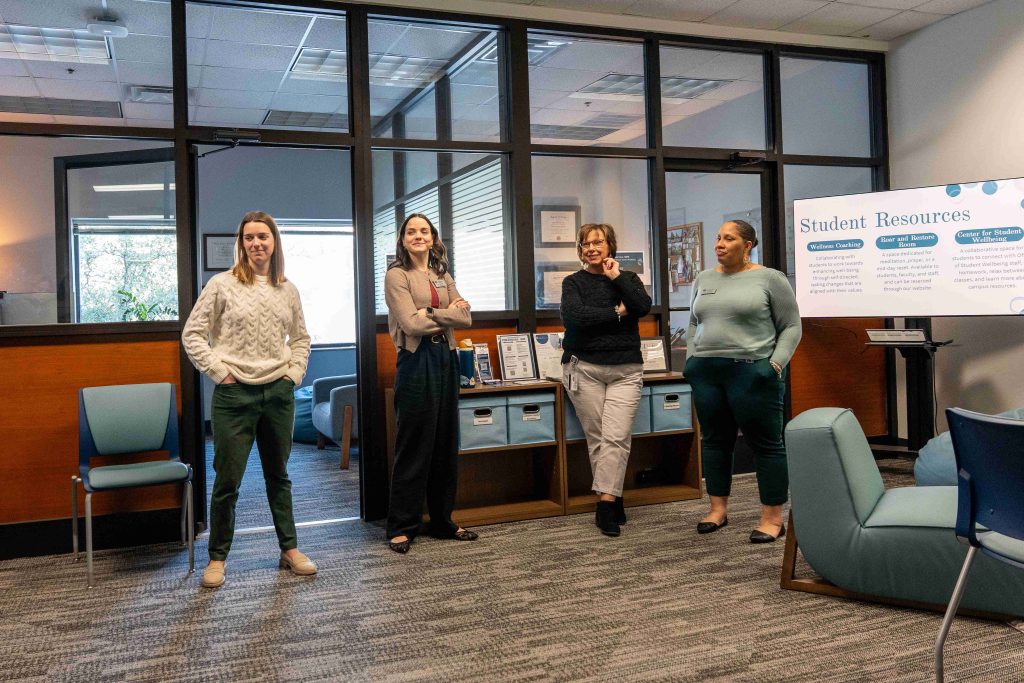 Four women talking amongst one another within an office space.