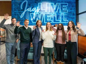 Several men and women hold up their hands in a paw pose.