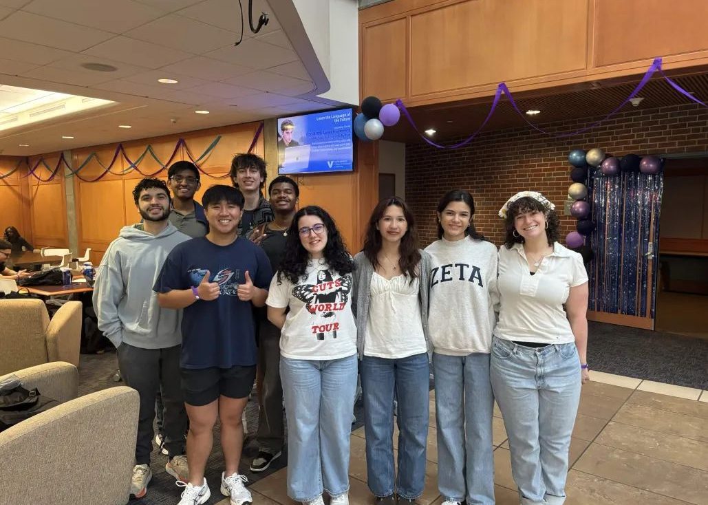 Students stand together smiling in a campus lounge.
