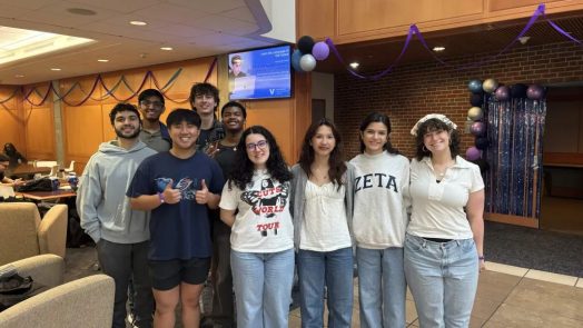 Students stand together smiling in a campus lounge.
