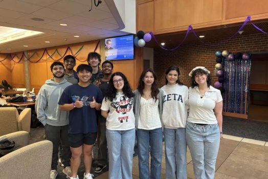 Students stand together smiling in a campus lounge.