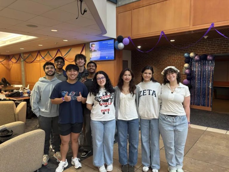 Students stand together smiling in a campus lounge.