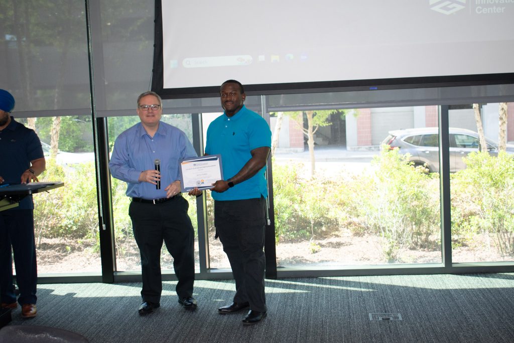 Student stands with his parents holding a certificate at a scholarship ceremony.