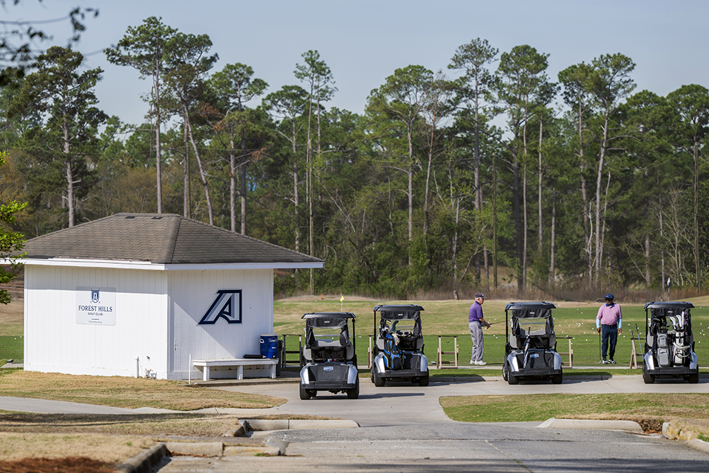 Golfers walking in front of golf carts near the driving range