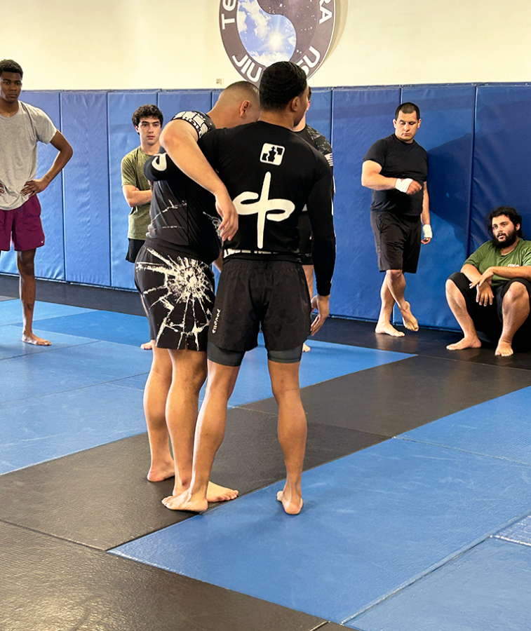Two men demonstrate a Jiu-Jitsu technique for a class.