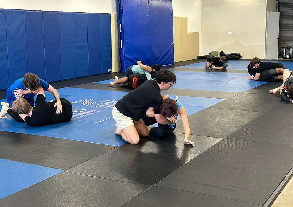 A group of people Jiu-Jitsu spar on a mat.