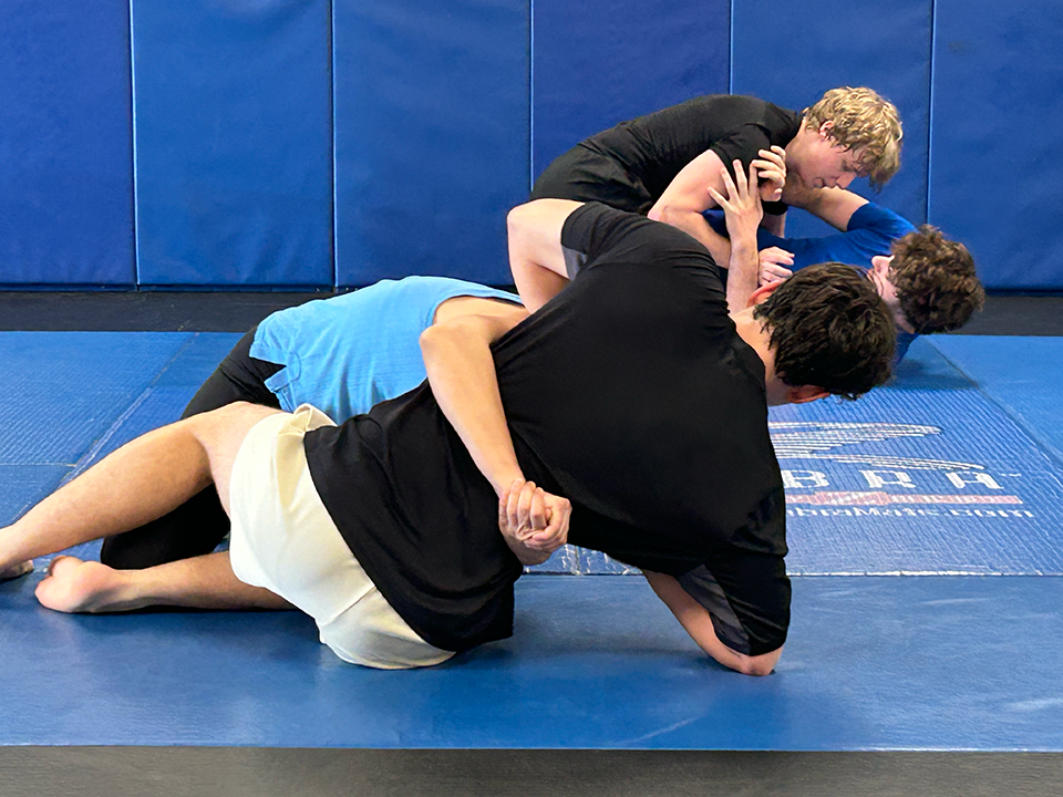 A man and a woman Jiu-Jitsu spar on a mat.