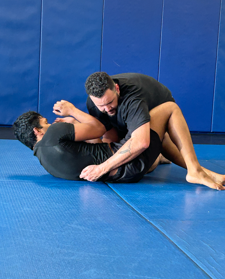 Two men Jiu-Jitsu spar on a mat.