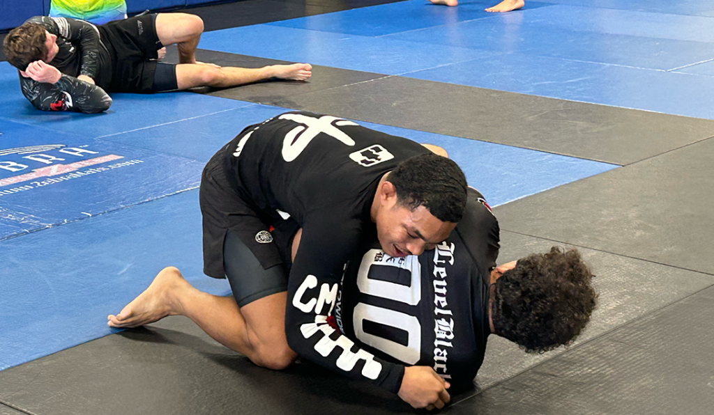 Two men Jiu-Jitsu spar on a mat.