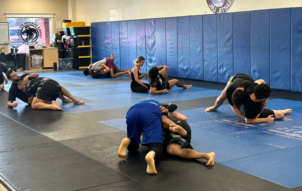 A group of people Jiu-Jitsu spar on a mat.
